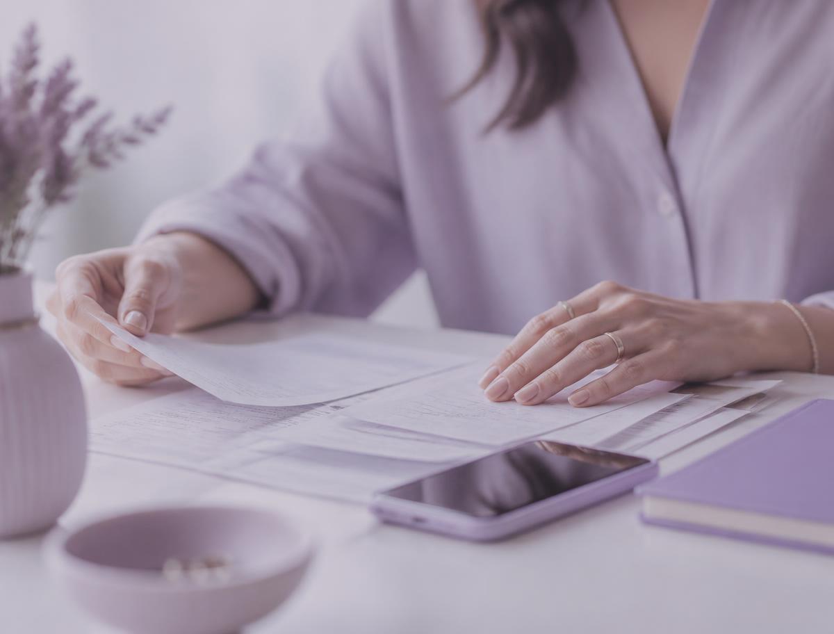 Mulher organizando documentos e comprovantes sobre uma mesa clara